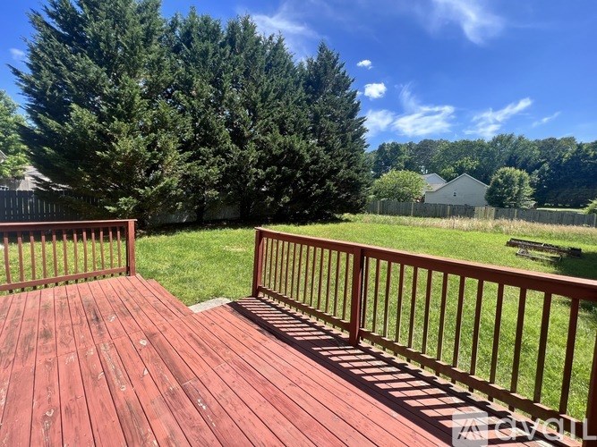 A wooden deck with a railing overlooking a grassy area.