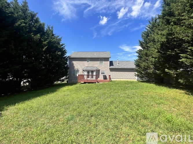 A house with a red door is surrounded by green grass and trees.