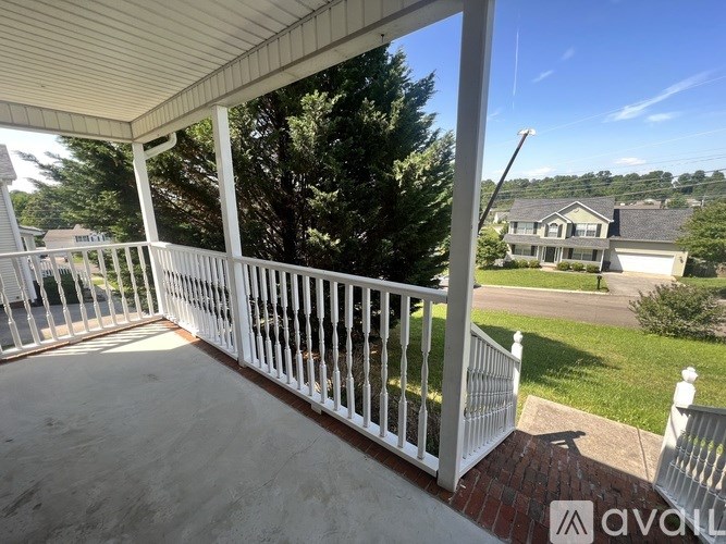 A white porch with a view of a residential neighborhood.
