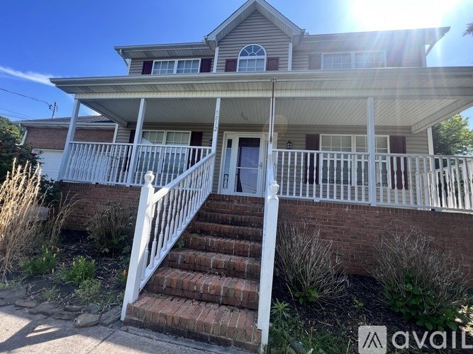 A house with a white porch and a brick staircase leading to the front door.