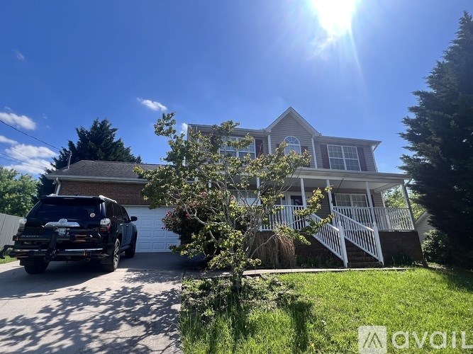 A house with a car parked in front and a tree to the left.