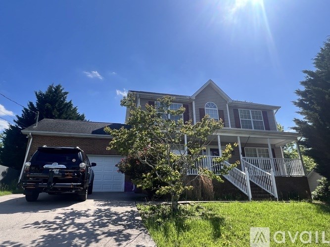 A house with a car parked in front and a tree to the left.