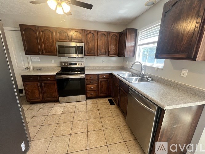A kitchen with wooden cabinets and a stainless steel dishwasher.