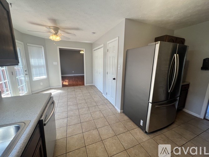 A kitchen with a refrigerator and a fan on the ceiling.
