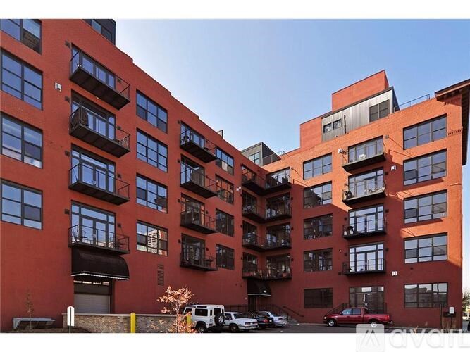 A red building with balconies and cars parked in front.