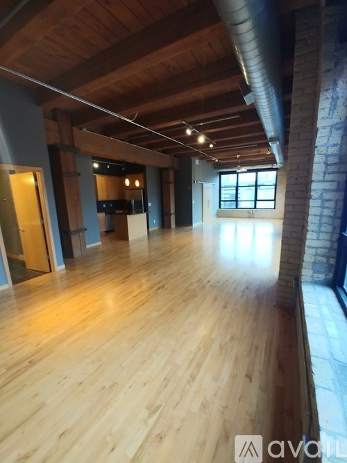A long hallway with wooden floors and a brick column on the side.