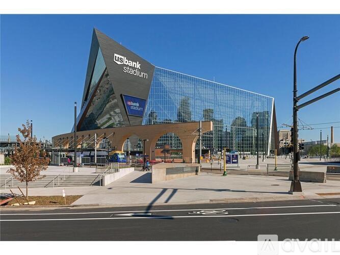 A modern stadium with a glass facade and a unique triangular roof.