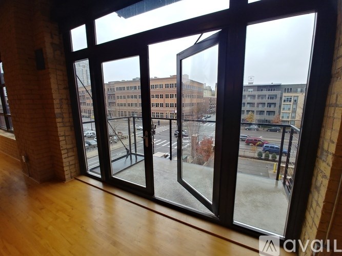 A view from inside a building looking out through a large window at a parking lot and other buildings.