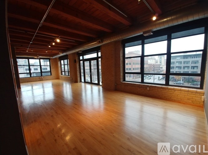 A large empty room with wooden floors and large windows.