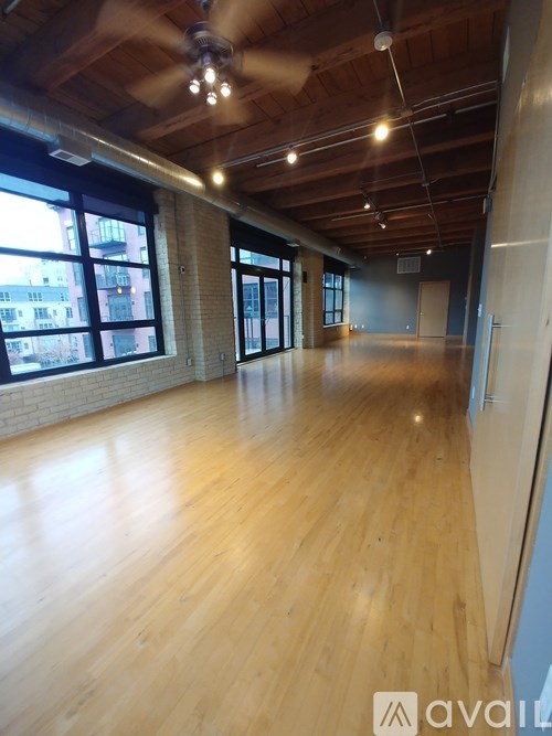 A spacious room with wooden floors and a ceiling fan.