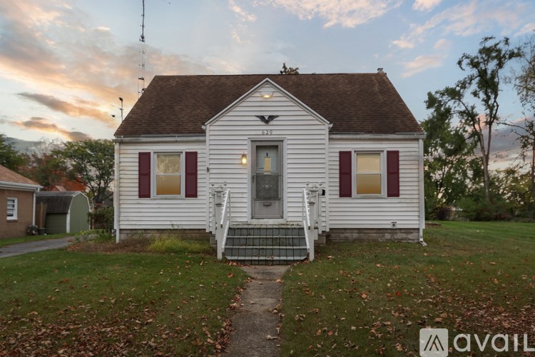 A white house with a brown roof and a small porch.