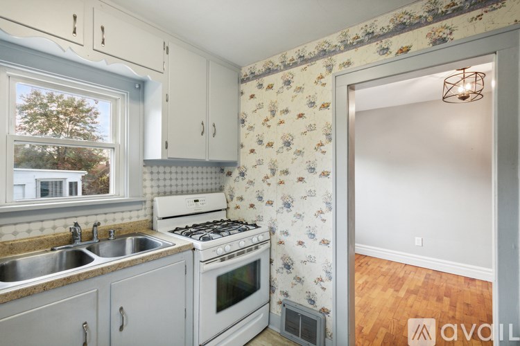 A kitchen with a floral wallpaper and a stove top oven.