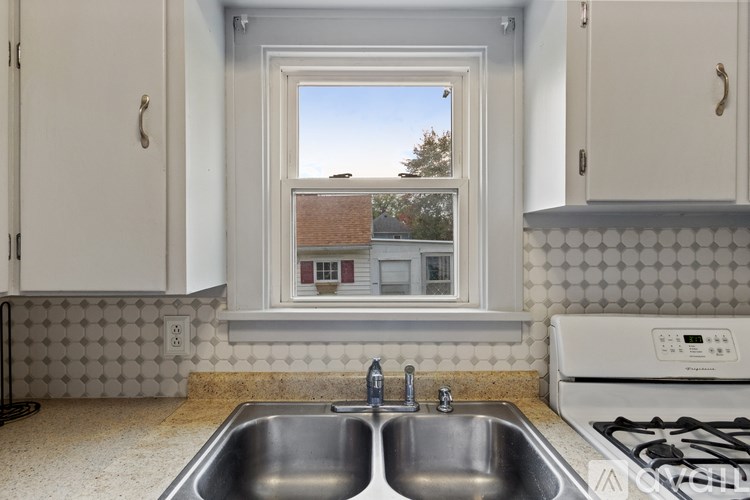 A kitchen with a window overlooking a house.