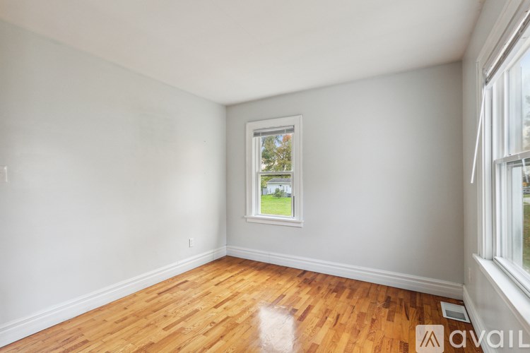 A room with wooden floors and a window showing a green outdoor scene.