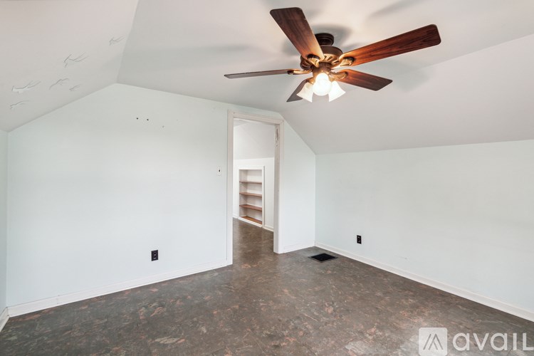 A room with a ceiling fan and a door leading to another room.
