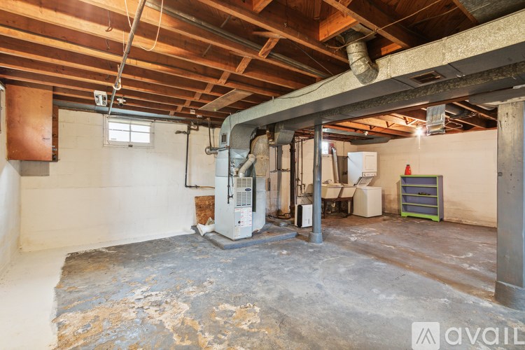 A room with a concrete floor and a white wall with a pipe running through it.