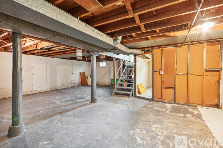A large empty room with a wooden ceiling and a ladder in the corner.