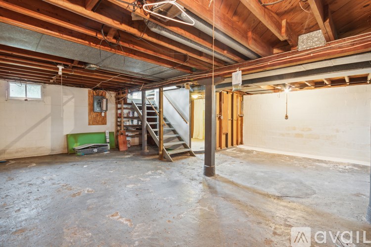 A large empty room with a staircase and a window.
