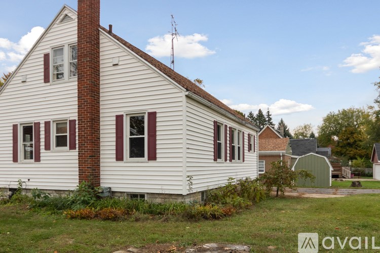 A white house with red shutters and a brick chimney.