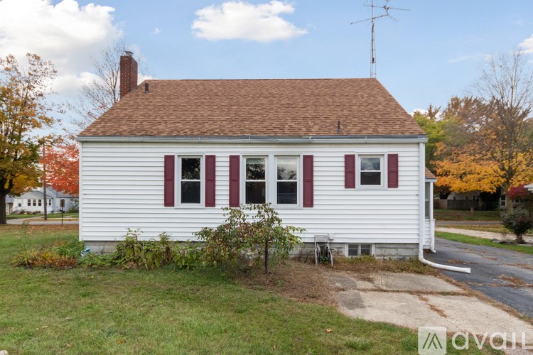 A small white house with red shutters and a brown roof.