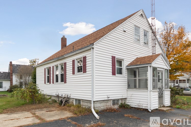 A white house with a brown roof and a porch.