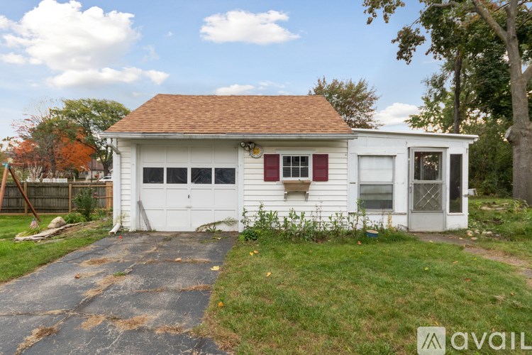A small white house with a red roof and a garage door.