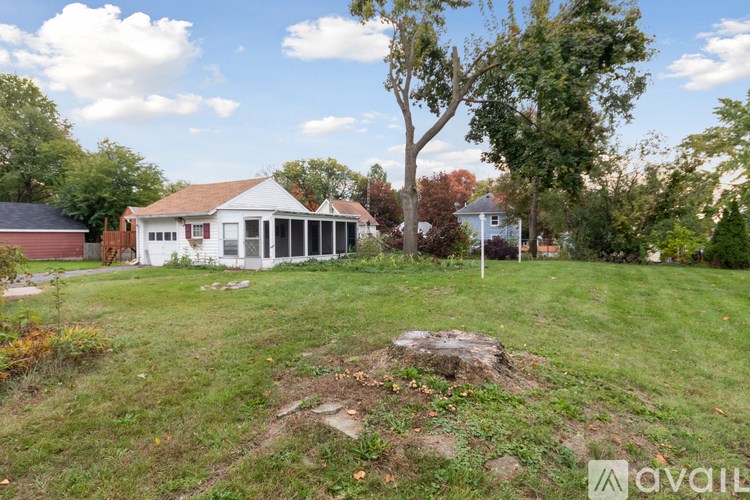 A white house with a red roof is surrounded by greenery.