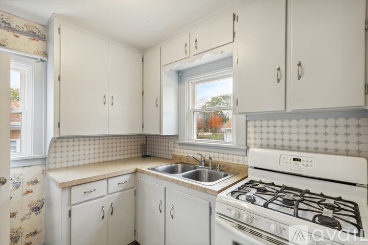 A small kitchen with a white gas stove and a window with a view of trees.