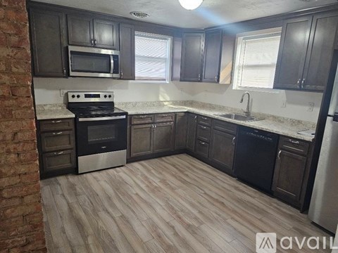 A kitchen with dark wood cabinets and a brick wall.