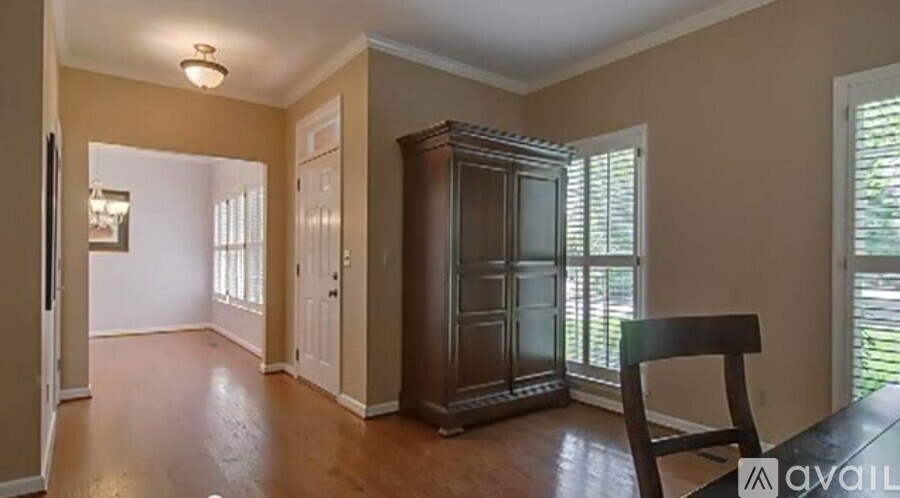 A room with a wooden floor, a brown cabinet, and a chair.