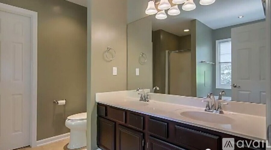 A bathroom with a white toilet and a large mirror above a sink.
