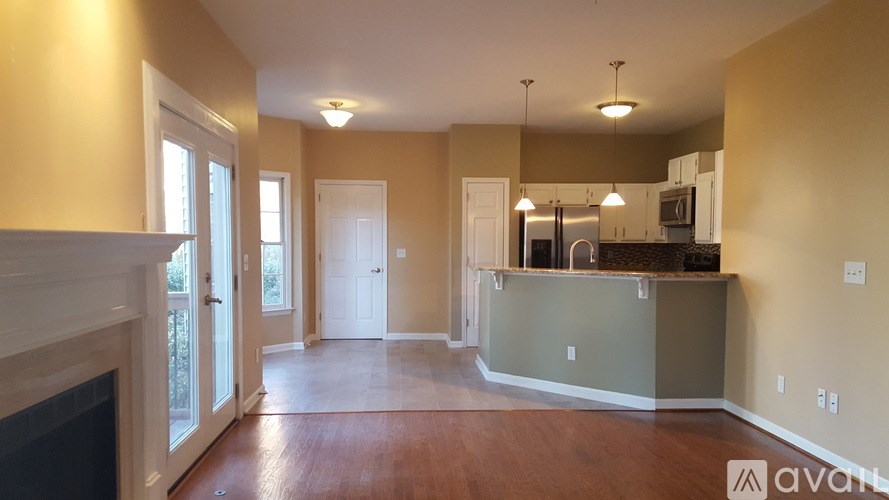 A spacious living room with a fireplace and a kitchen area in the background.