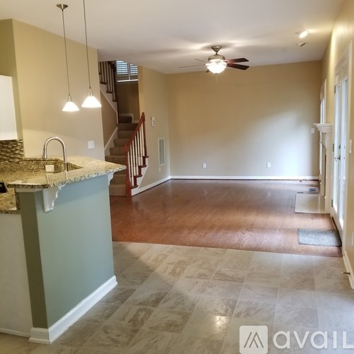 A kitchen with a marble countertop and a staircase in the background.