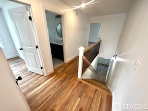 A wooden staircase with a metal railing leads up to a bedroom.