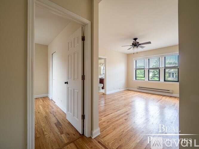 A room with a white door and a ceiling fan.
