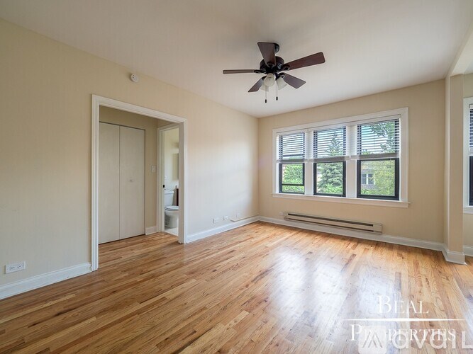 A room with a ceiling fan and wooden flooring.