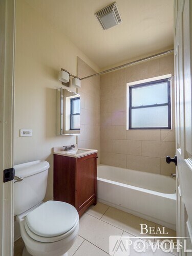A white toilet sits next to a bathtub in a bathroom.
