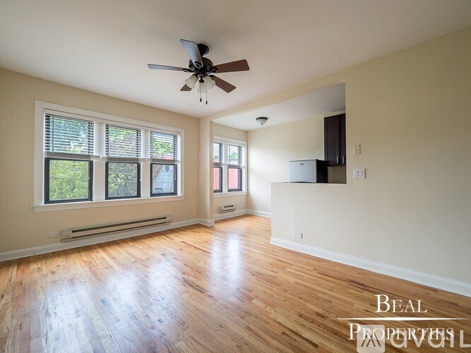 A spacious room with a ceiling fan and wooden flooring.