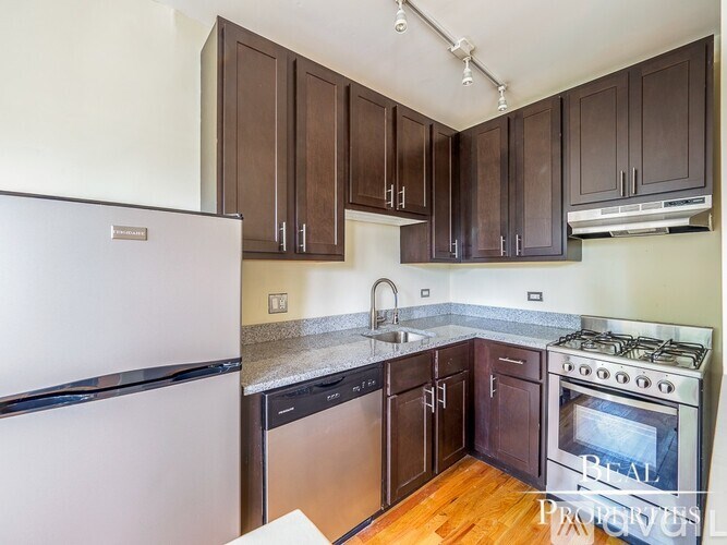 A kitchen with brown cabinets and a white fridge.