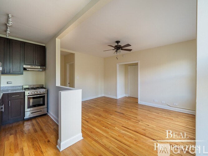 A spacious room with wooden floors and a ceiling fan.