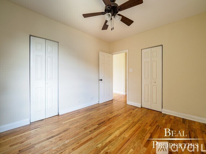 A room with a ceiling fan and wooden floors.