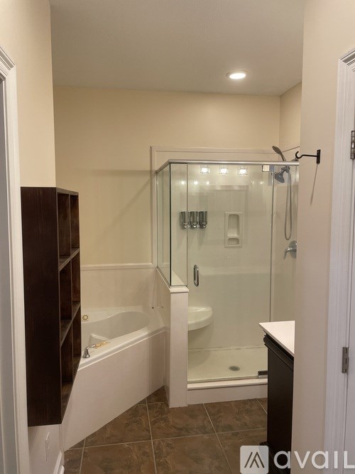 A bathroom with a glass shower enclosure and a white bathtub.