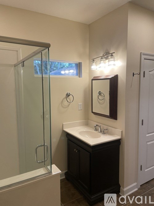 A bathroom with a sink, mirror, and shower.
