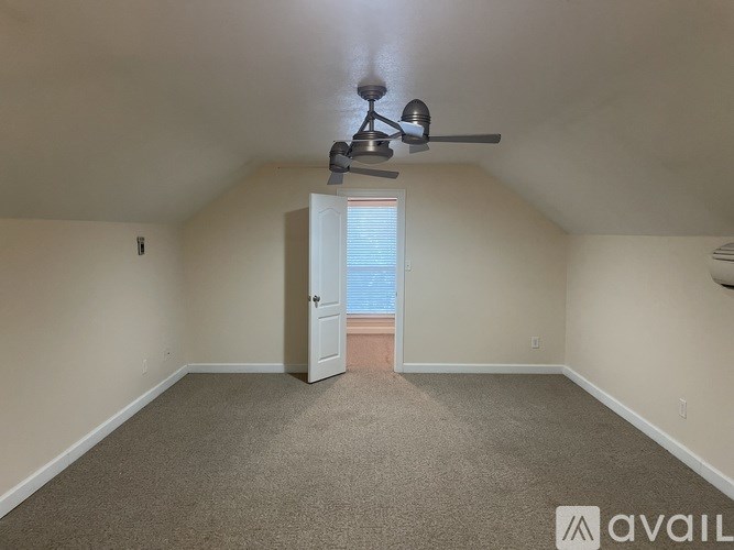 A room with a ceiling fan and a door leading to a balcony.