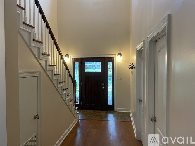 A hallway with a staircase leading to a door.