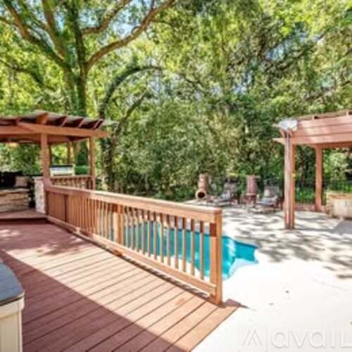 A wooden deck with a pool in the background.