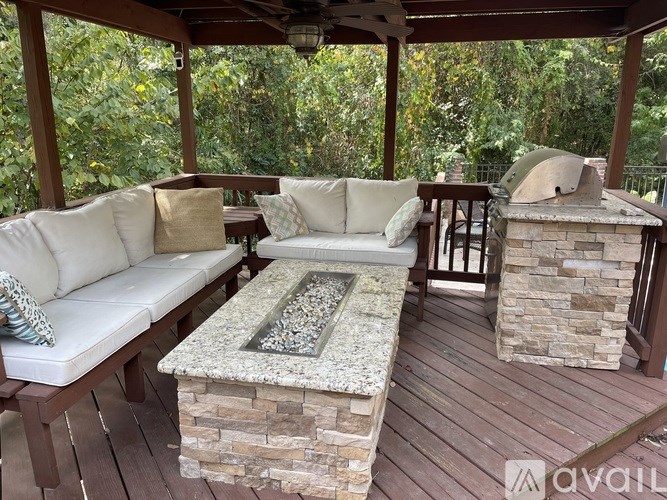 A wooden deck with a couch and a stone fireplace.