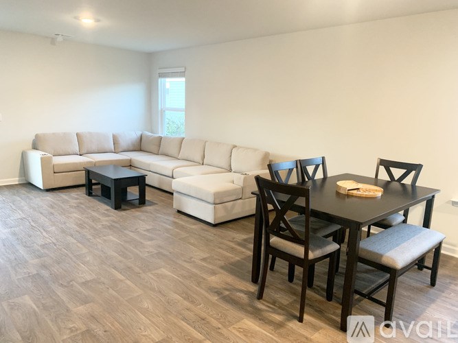 A living room with a white couch, a black table, and a wooden floor.