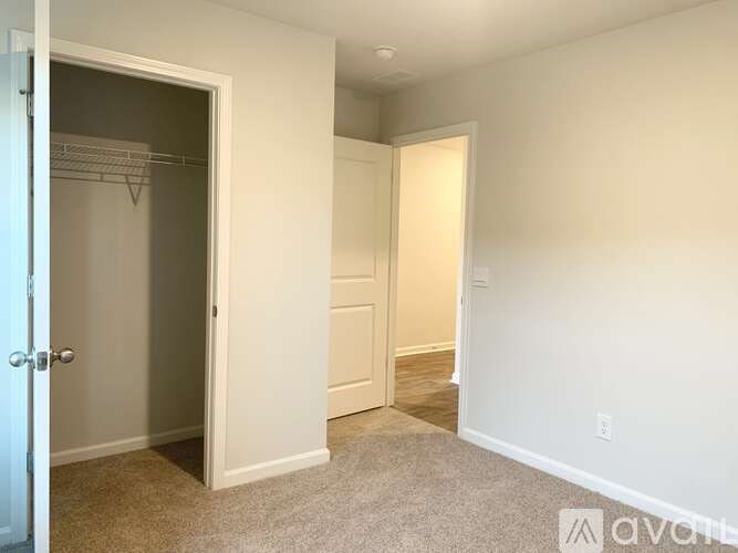 A white door is open to a hallway with a carpeted floor.