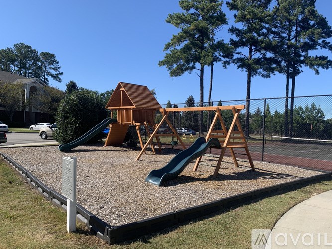 A playground with a green slide and a wooden swing set.